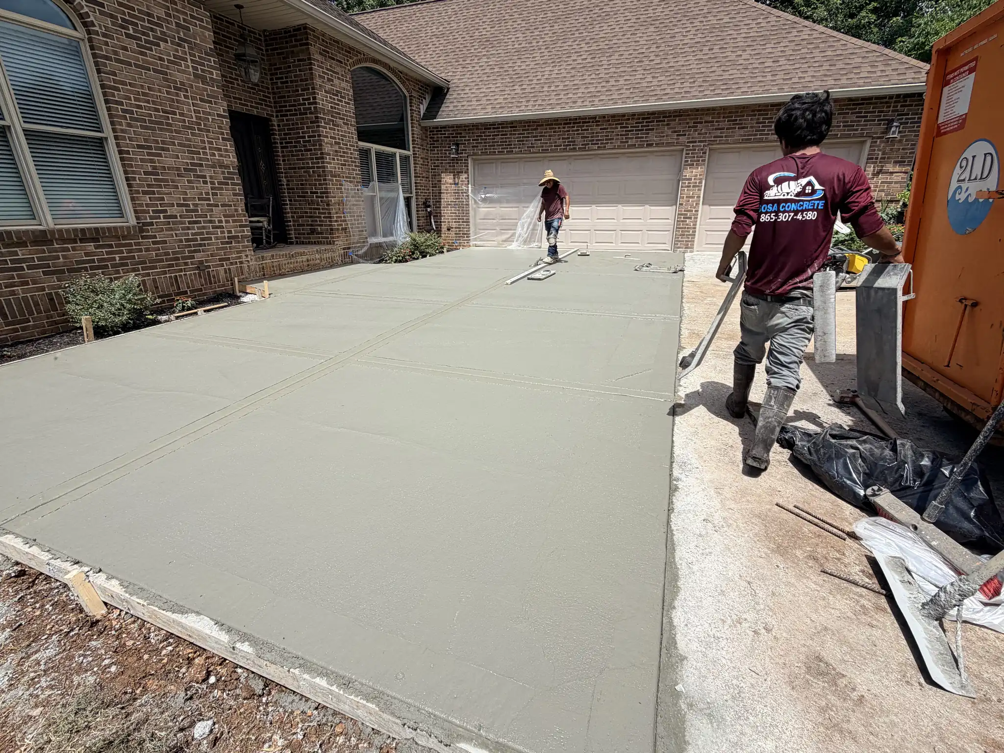 Sosa Concrete crew finishing a new concrete driveway at a brick home in Knoxville, Tennessee